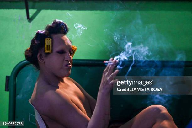 Contestant smokes a cigarette at the Miss Gay pageant's backstage, as their transgender community celebrates the Feast of Sto. Niño in Tondo, Manila...