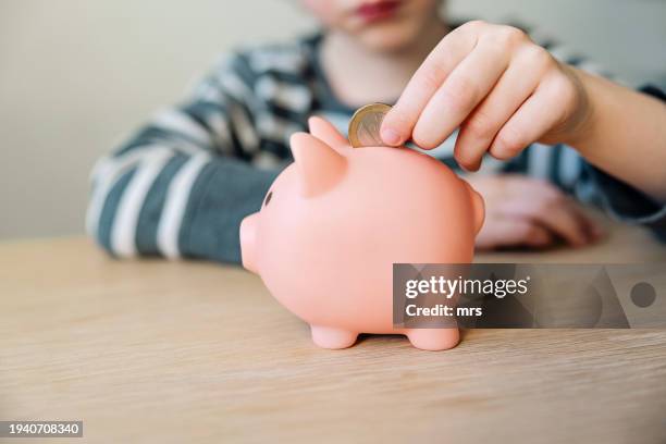child putting coins into a piggy bank - spaarpot financieel item stockfoto's en -beelden