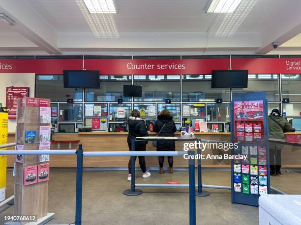 People queue at the counter inside a branch of the Post Office on January 16, 2024 in Keynsham, England. On January 10 the British Prime Minister...