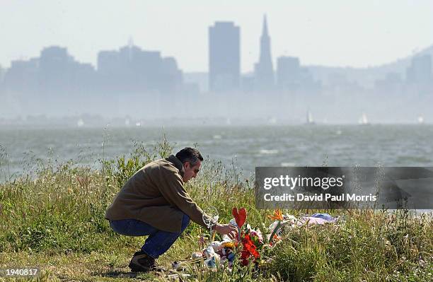 Michael Accurso of El Sobrante, California pours water on some flowers at a memorial that includes flowers, candles and stuffed toys April 19, 2003...