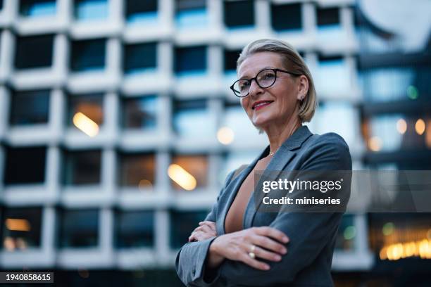 portrait d’une femme d’affaires âgée confiante et belle debout devant l’immeuble de bureaux le soir - directeur général photos et images de collection