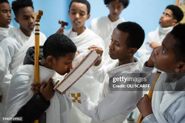 Worshippers are offered a holy book to touch with their head during a service to celebrate Timket, or the feast of Epiphany, in the Eritrean Orthodox...