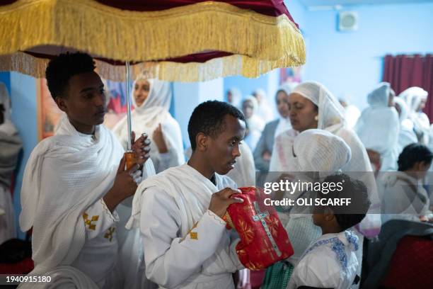 Worshippers are offered a holy book to touch with their head during a service to celebrate Timket, or the feast of Epiphany, in the Eritrean Orthodox...