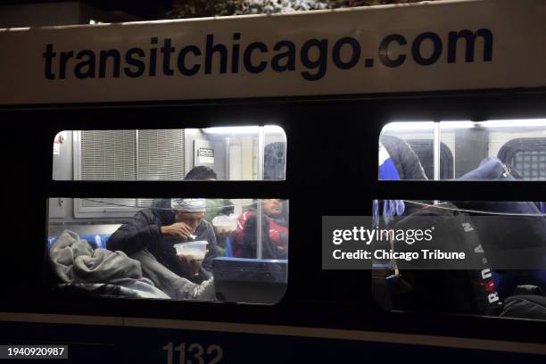 Outside the 1st District police station, migrants eat and take a break from the cold weather on a Chicago Transit Authority warming bus on Oct. 30,...