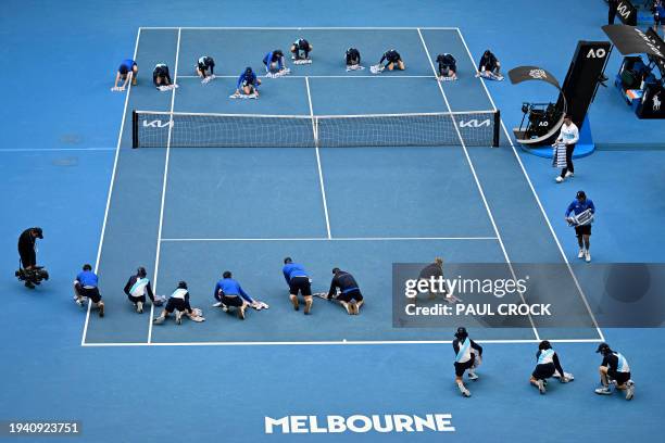 Staff and volunteers help to dry the court during the women's singles match between USA's Amanda Anisimova and Belarus' Aryna Sabalenka on day eight...