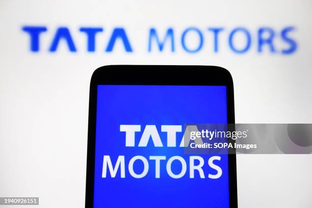 In this photo illustration, the Tata Motors Limited logo is seen on a smartphone and in the background.