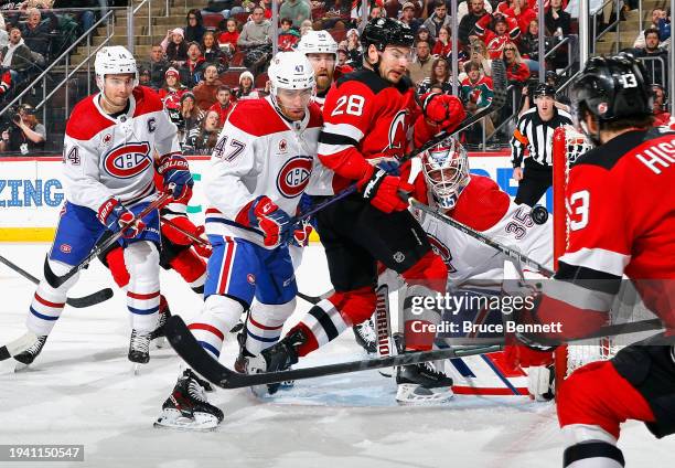 Jayden Struble of the Montreal Canadiens checks Timo Meier of the New Jersey Devils as Sam Montembeault makes the second period save at Prudential...