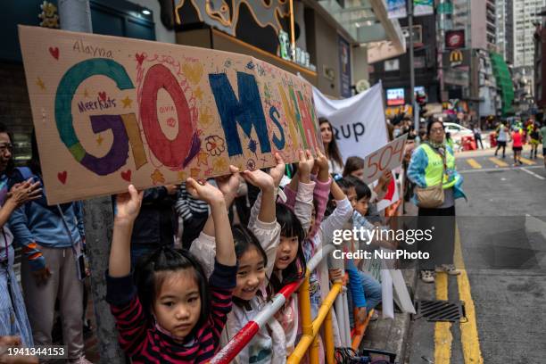 Children are holding up a sign they made to cheer for their teacher who is running in the 2024 Hong Kong Marathon in Hong Kong, on January 21, 2024.