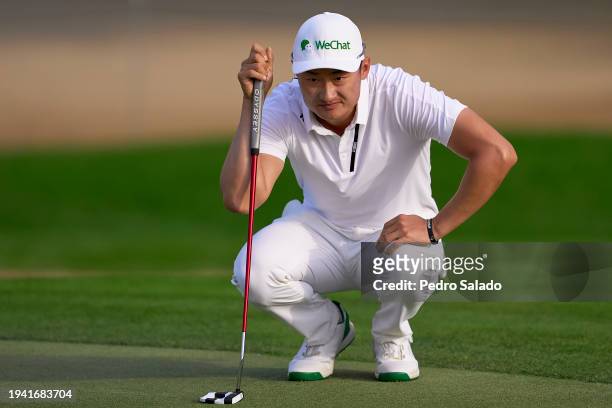Haotong Li of China lines a putt on the third green during the first round of the Hero Dubai Desert Classic on the Majlis Course at Emirates Golf...