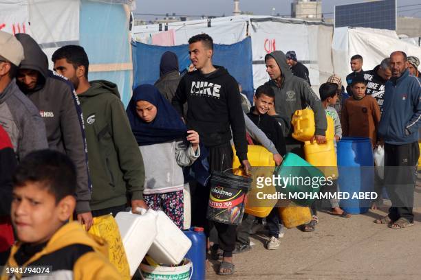 Palestinians queue to get water during a distribution organised by "Doctors Without Borders" NGO at a makeshift tent camp in Rafah near the border...