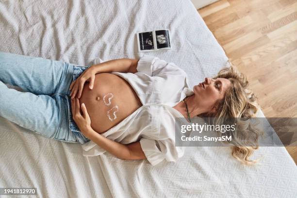 pregnant woman embracing her belly - fetus heart stock pictures, royalty-free photos & images