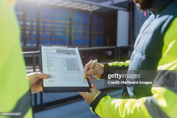 close up of clipboard with cargo details. warehouse receiver talking with truck driver, holding tablet, checking delivered items, goods against order - loading bay stock pictures, royalty-free photos & images