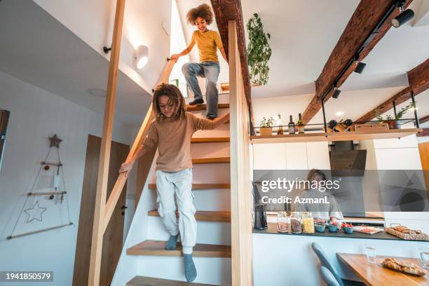 diverse family enjoying time at home with children descending stairs and mother cooking in kitchen - family and happiness and diverse imagens e fotografias de stock