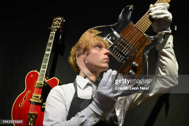 An auction house employee holds up a see-through Dan Armstrong-Ampeg electric guitar owned by musician Mark Knopfler at a media event to promote an...