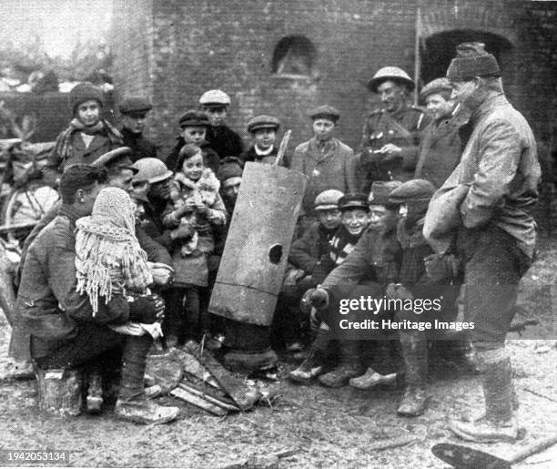 Delivres ! ; La population enfantine d'un village libere se presse autour d'un brasero improvise par les Anglais', 1917. From "L'Album de la Guerre...