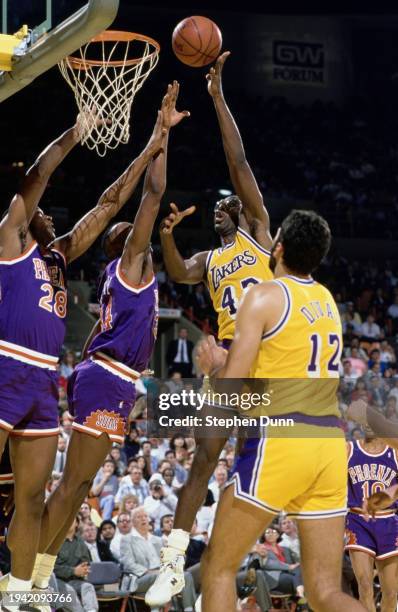 James Worthy, Small Forward and Power Forward for the Los Angeles Lakers attempts a jump shot to the basket over the blocking of Tim Perry, Power...