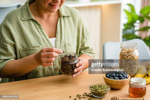 frau isst bio-rosinen aus glas - rosine stock-fotos und bilder
