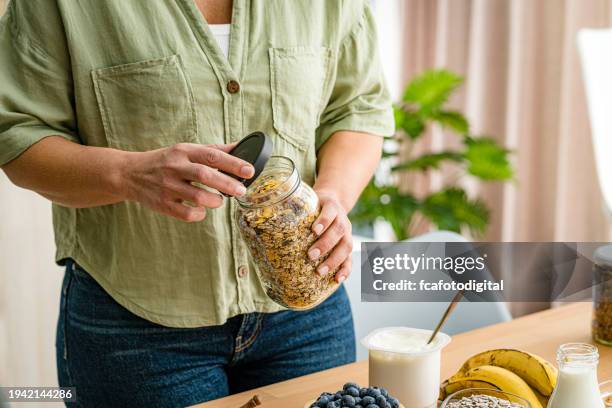 woman holding oatmeal and dried fruits jar. healthy eating concept - yoghurt lid stock pictures, royalty-free photos & images