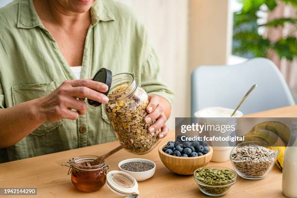woman preparing healthy vegan and nutritious breakfast. oatmeal , honey, berries, seeds, fruits - yoghurt lid stock pictures, royalty-free photos & images