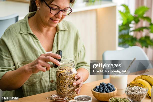 la mujer está a punto de preparar un desayuno saludable y nutritivo. avena, miel, bayas, semillas, frutas - fibra dietética fotografías e imágenes de stock