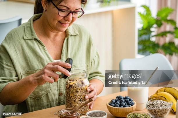 woman is about to prepare healthy nutritious breakfast. oatmeal , honey, berries, seeds, fruits - fibre food stockfoto's en -beelden