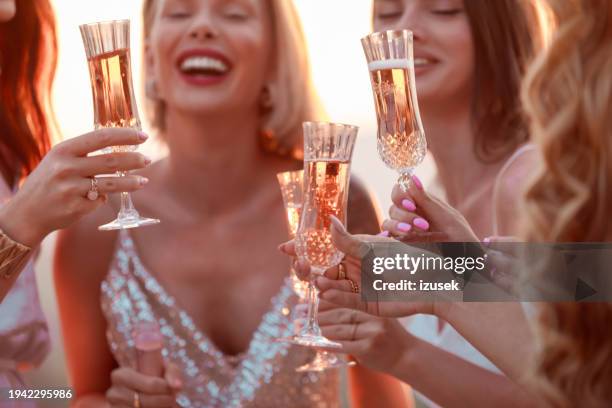 female friends drinking champagne during bachelorette party at sunset - celebratory toast stock pictures, royalty-free photos & images