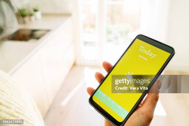 top view of woman hands holding a phone showing the meteorology forecast on the screen. - meteorologie stockfoto's en -beelden