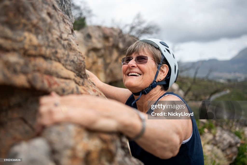 Mulher sênior sorridente se divertindo durante a aventura de escalada