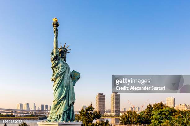 statue of liberty replica and tokyo skyline on a sunny day, tokyo, japan - réplica da estátua da liberdade imagens e fotografias de stock