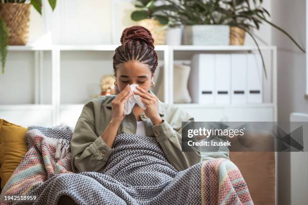 mujeres jóvenes preocupadas sentadas en el sofá de casa - gripe fotografías e imágenes de stock