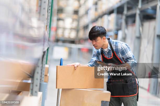 warehouse operator checking inventory with digital tablet, a focused warehouse operator is standing in an aisle, holding a digital tablet and verifying inventory against a digital device. - cardboard box stock pictures, royalty-free photos & images