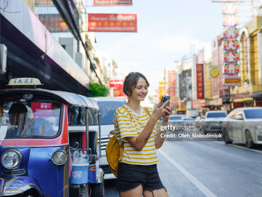 Woman using smartphone while walking in Chinatown in Bangkok