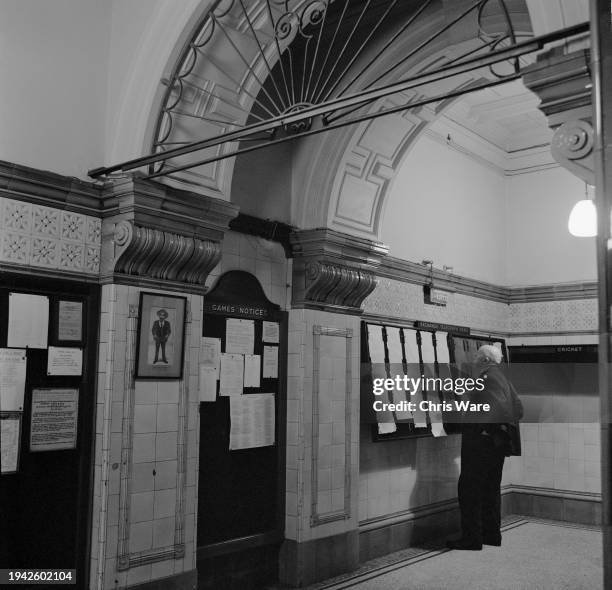 Man reading the 'Exchange Telegraph News' on a noticeboard at the National Liberal Club, a private members' club on the Thames Embankment, London,...