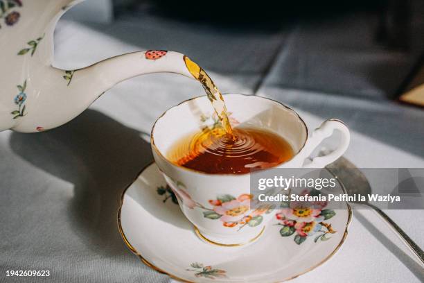 vintage teapot pouring tea in tea cup - tea fotografías e imágenes de stock