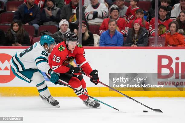 Kevin Korchinski of the Chicago Blackhawks skates with the puck against Mike Hoffman of the San Jose Sharks during the first period at the United...