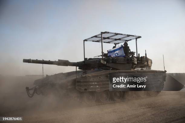 Israeli soldiers hold an Israeli flag on a tank that is moving along the border with Gaza Strip on January 21, 2024 in Southern Israel, Israel....