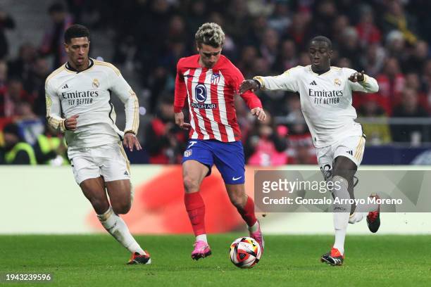 Antoine Griezmann of Atletico Madrid is challenged by Ferland Mendy and Jude Bellingham of Real Madrid during the Copa del Rey Round of 16 match...