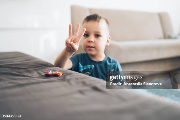 little boy showing three fingers while playing at home - three fingers stock pictures, royalty-free photos & images