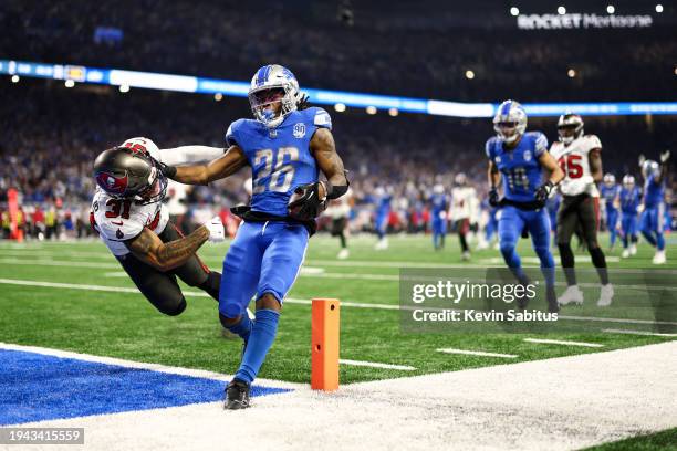 Jahmyr Gibbs of the Detroit Lions stiff arms Antoine Winfield Jr. #31 of the Tampa Bay Buccaneers while scoring a touchdown during the fourth quarter...