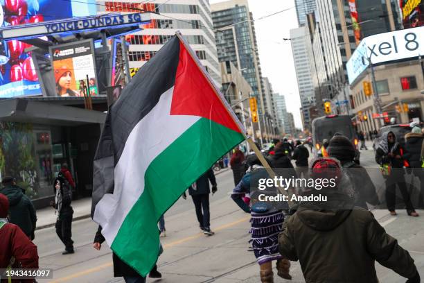 Man waves a Palestinian flag at Yonge-Dundas Square as hundreds march during a rally in Toronto, Ontario on January 21, 2024. Demonstrators demanding...