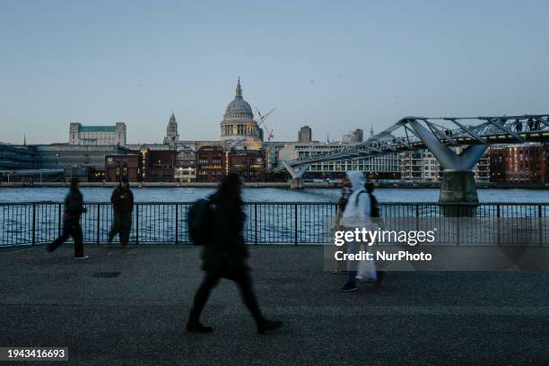 People are walking on the south bank of the River Thames as the sun sets in London, England, on January 16, 2024.