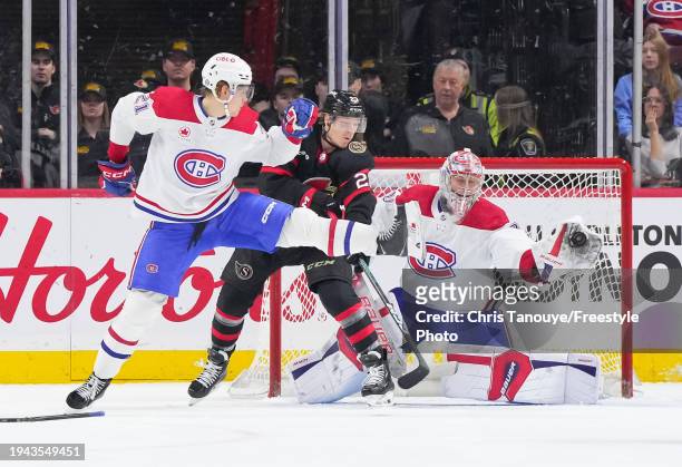 Cayden Primeau of the Montreal Canadiens makes a glove save as teammate Kaiden Guhle attempts to block the puck while battling with Parker Kelly of...