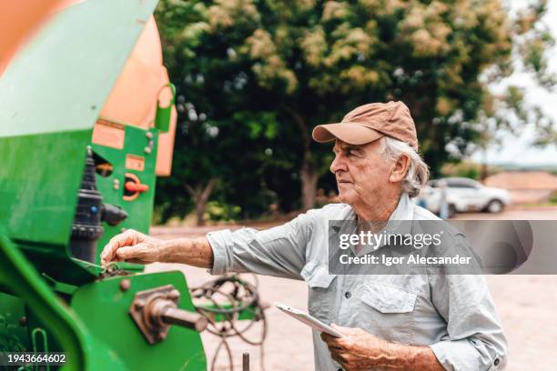 farmer setting up agricultural machine - agricultural equipment stock pictures, royalty-free photos & images