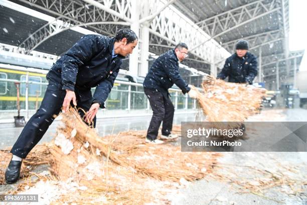 Staff members are laying anti-slip straw mats on the platform of Nanchang Railway Station in Nanchang, China, on January 22, 2024.