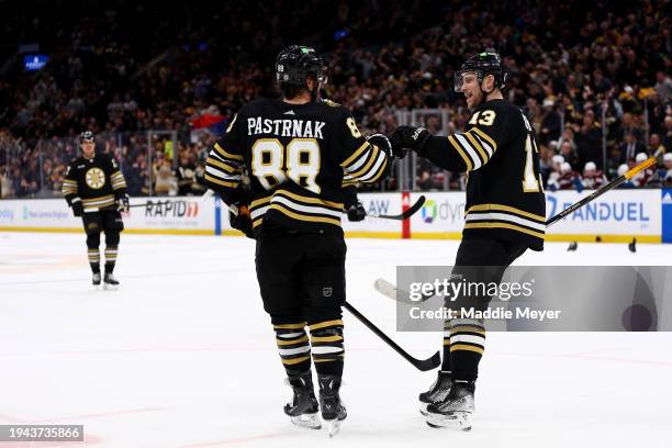 David Pastrnak of the Boston Bruins celebrates with Charlie Coyle after scoring a hat-trick goal against the Colorado Avalanche during the third...