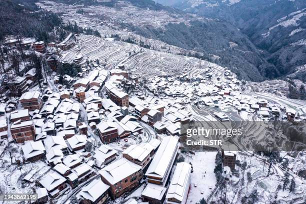 The aerial view shows snow-covered terraced fields and houses in Congjiang county, in China's southwestern Guizhou province on January 22, 2024. /...