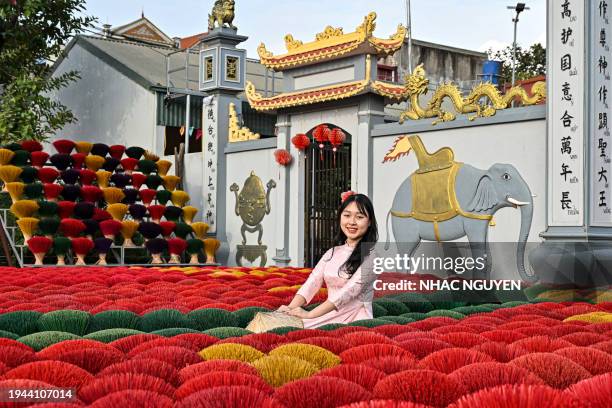 In this photo taken on January 20, 2024 a tourist poses in front of incense sticks arranged in the form of a Vietnamese map and flag in a courtyard...