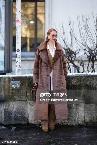 Guest wears sunglasses, a white shirt, a waistcoat, a brown long fluffy faux fur coat, brown pants, pointed shoes, outside Issey Miyake, during the...