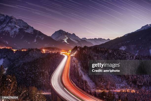 notte d'inverno con le stelle e i sentieri di luce, l'autostrada sul ponte in montagna - stelle cadenti foto e immagini stock