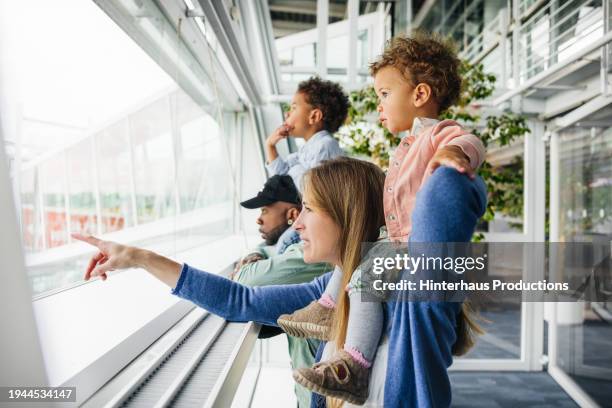 family watches planes as they take off - woman blond looking left window stockfoto's en -beelden
